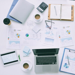 Scattered resources like documents and laptop & coffee on a desktop